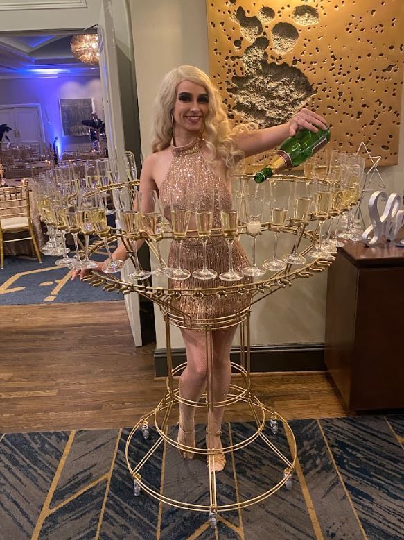 A woman is pouring champagne into a glass tower.
