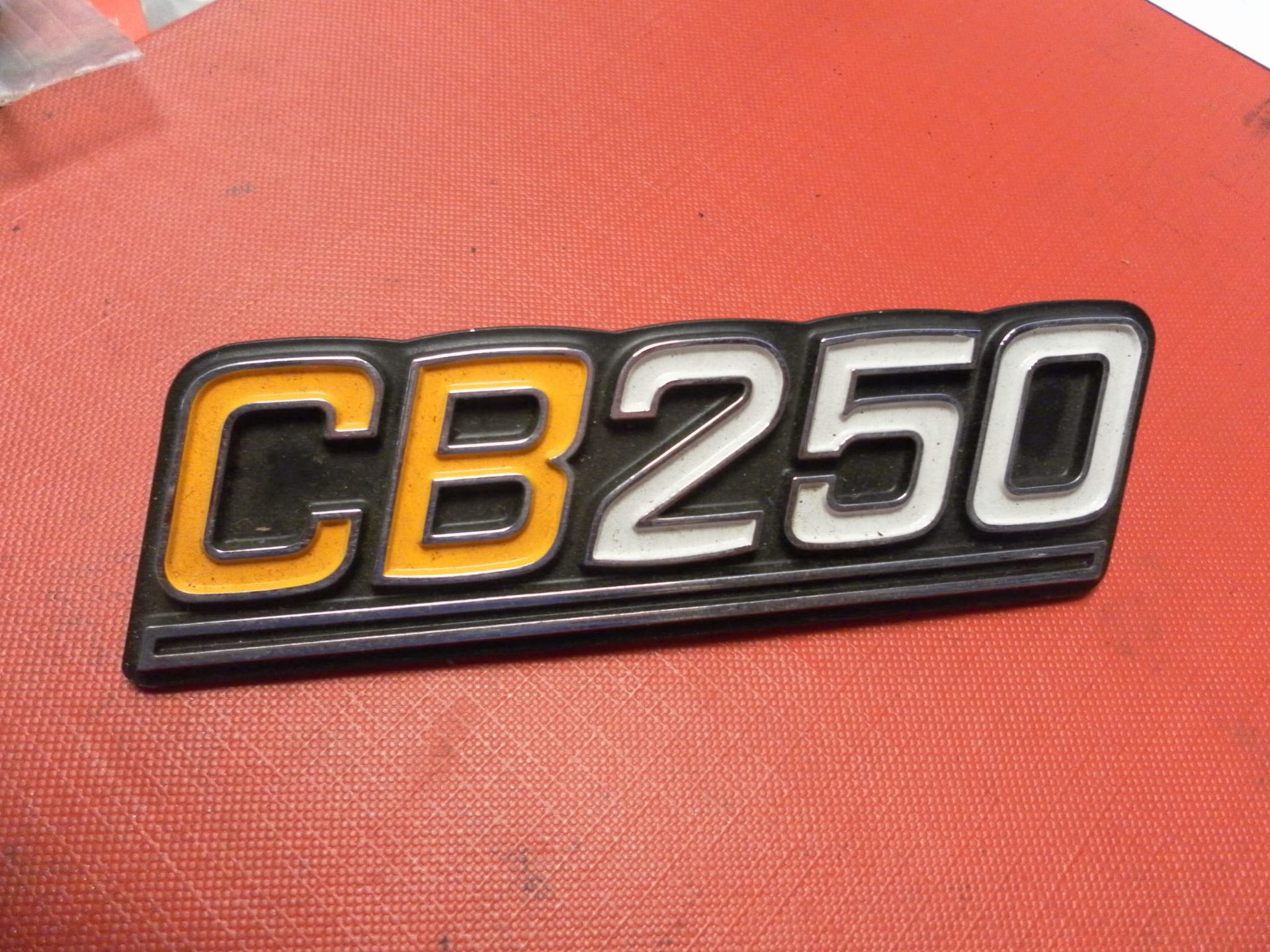 embleem zijkap cb250 . Kunstof oranje / wit / zwart