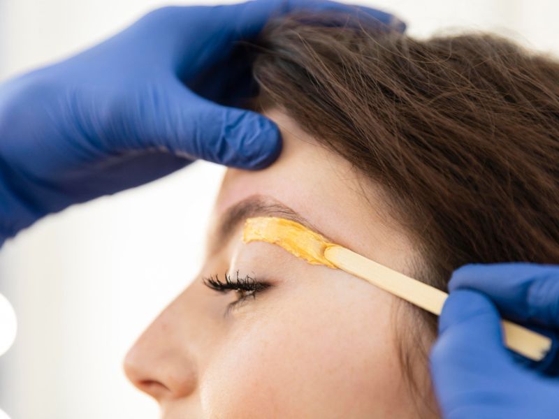 Woman having eyebrow waxed