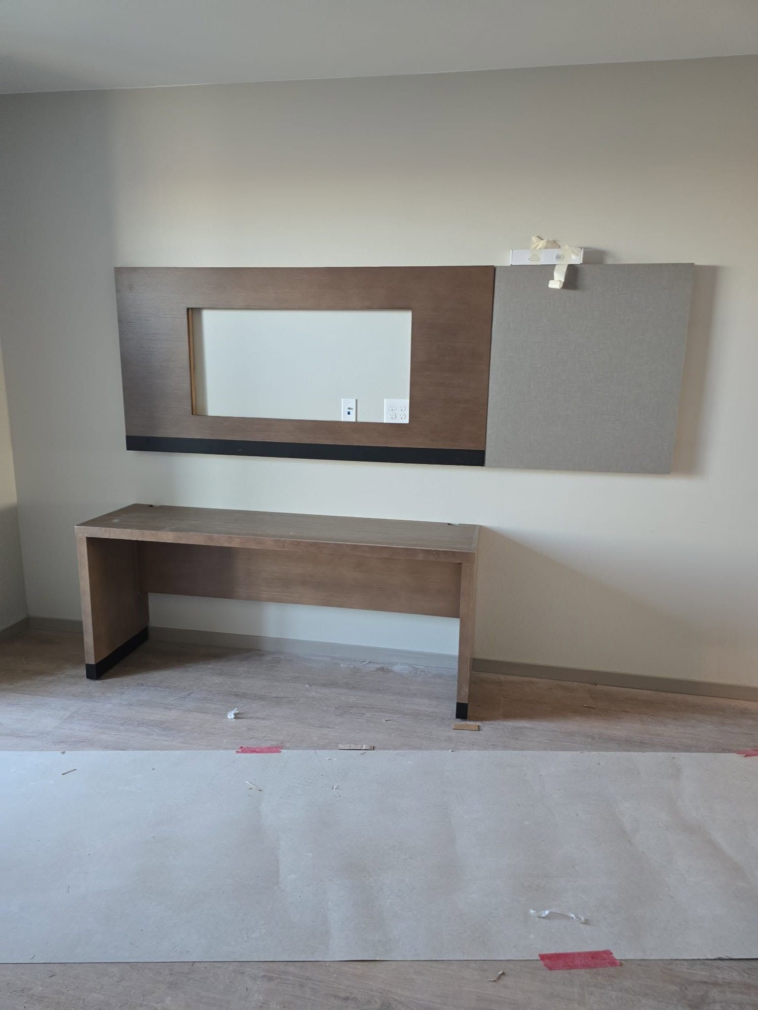 Empty room with a wall-mounted vanity and large mirror above a wooden counter and sink area.