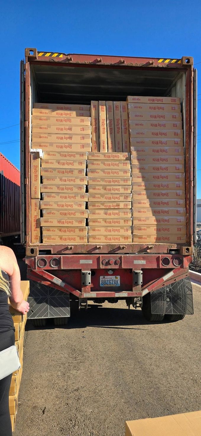 Open truck loaded with stacked cardboard boxes in a gravel yard