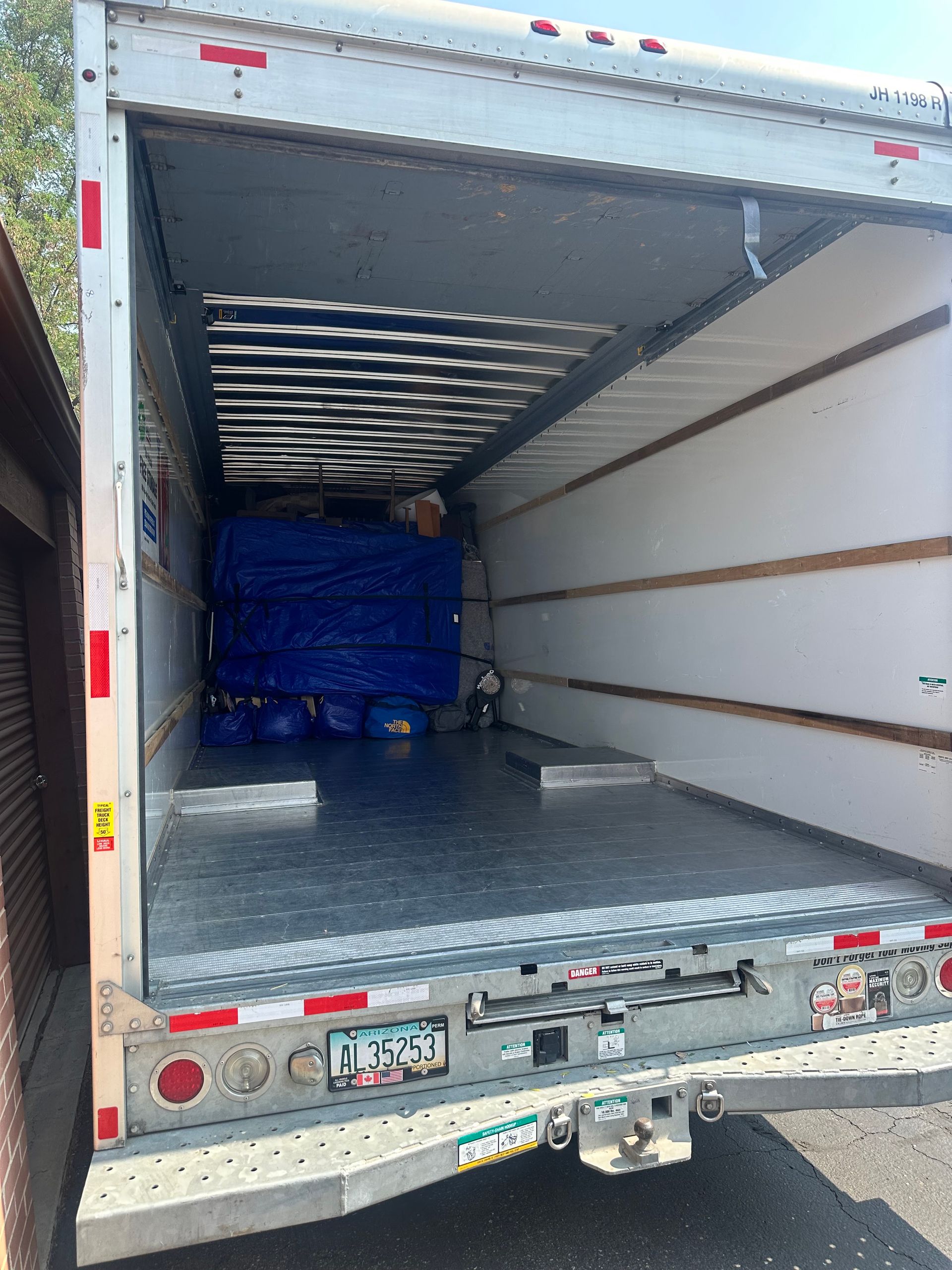 Inside an open box truck, blue pallets are stacked near the front of the cargo area.