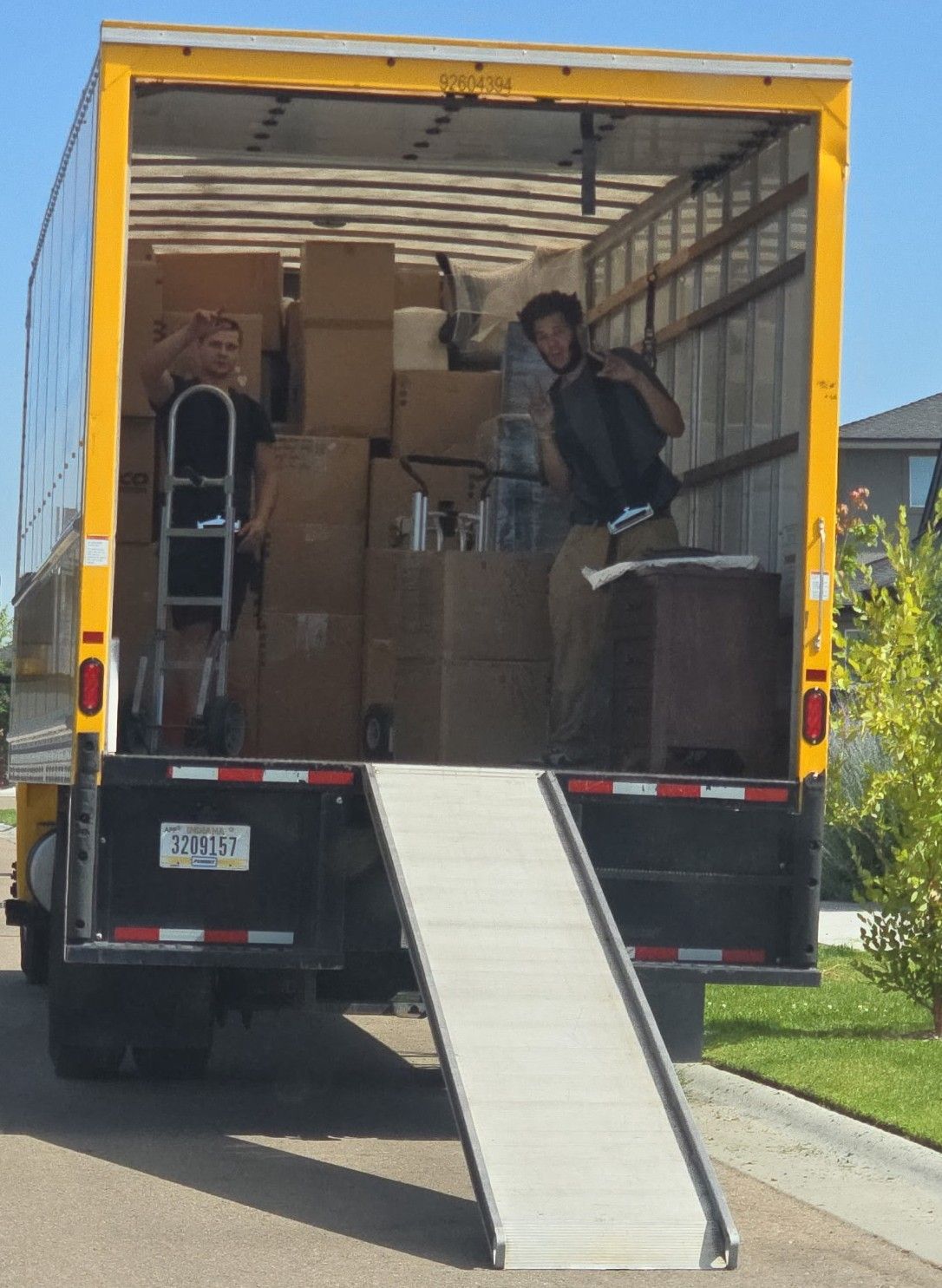 Moving truck with open rear ramp, boxes stacked inside, and a person standing near the doorway.