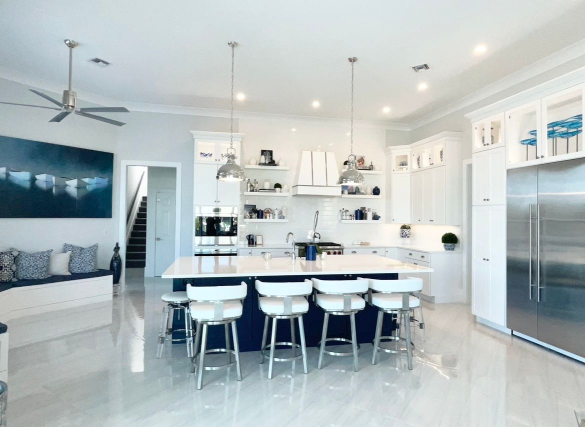 Bright modern white kitchen with island seating, stainless fridge, and open living area at CRAFTED 1111 fashion
