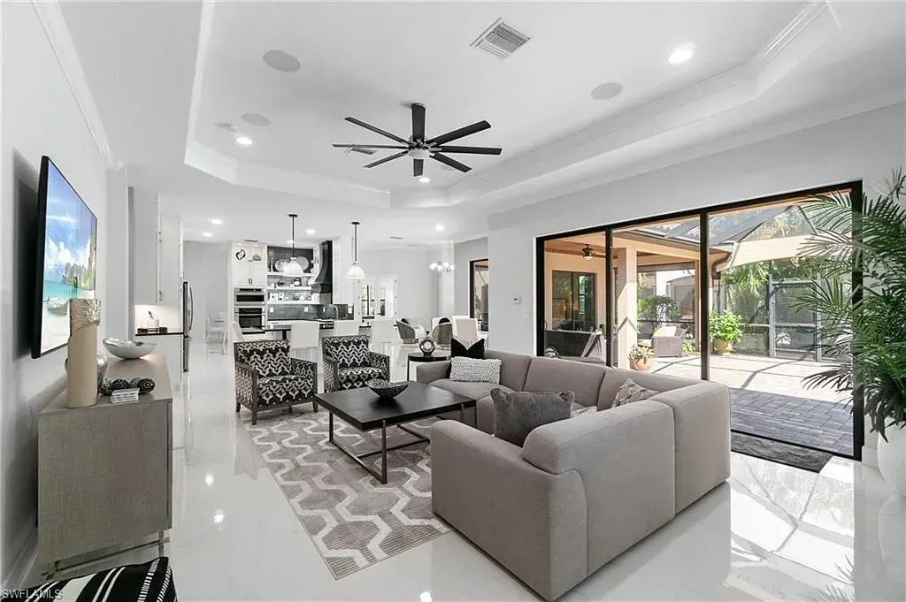 Bright modern living room with gray sectional, black ceiling fan, and open patio doors to a pool area at CRAFTED 1111 fashion