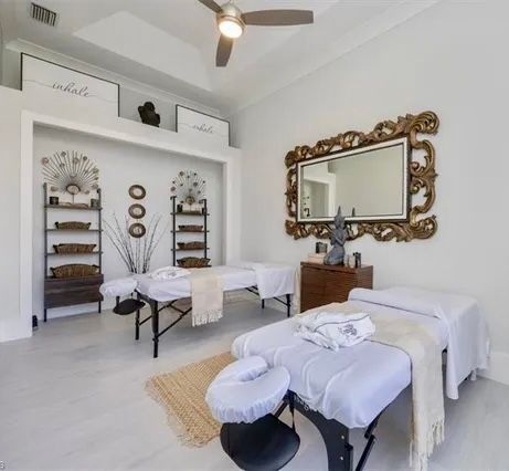 Bright spa treatment room with two massage tables, white decor, and an ornate gold mirror at CRAFTED 1111 fashion