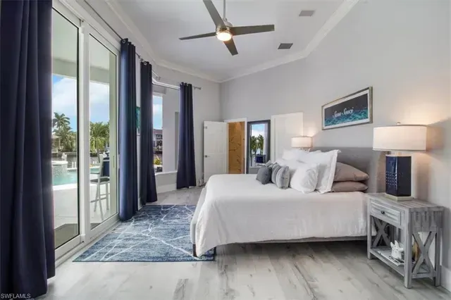 Bright modern bedroom with king bed, blue rug, large windows, ceiling fan, and pool view at CRAFTED 1111 fashion