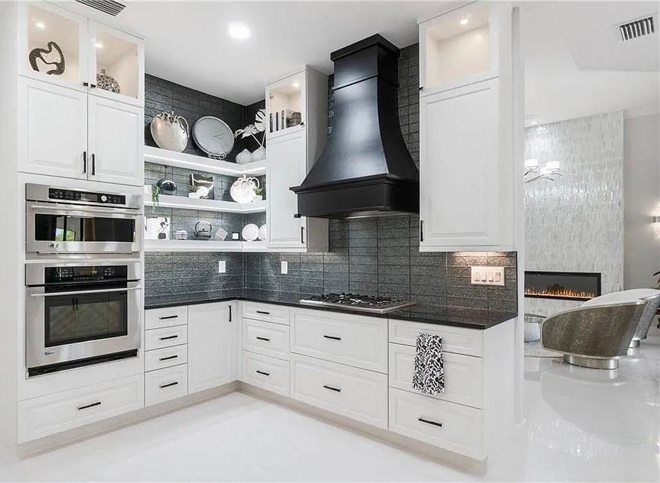 Bright modern white kitchen with black range hood, dark backsplash, and built-in ovens at CRAFTED 1111 fashion