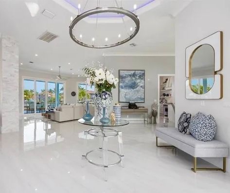 Bright modern living room with white floors, circular chandelier, gray sofa, and glass coffee table with flowers at CRAFTED 1111 fashion