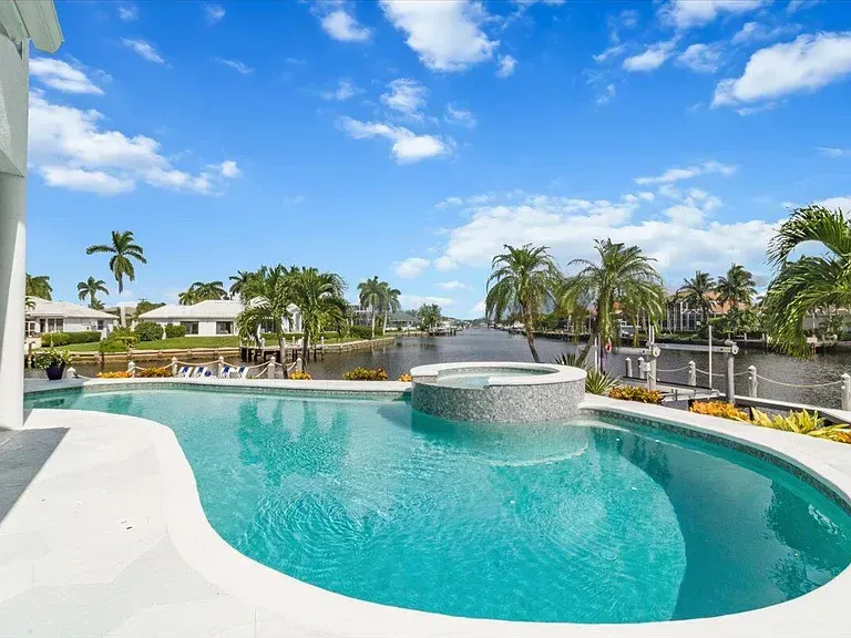 Luxury resort pool with turquoise water, palm trees, and blue sky on a sunny day at Crafted 1111