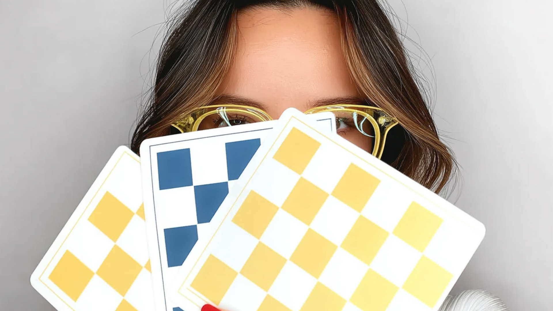 Person holding three patterned notebooks in front of their face, wearing gold glasses at CRAFTED 1111 fashion