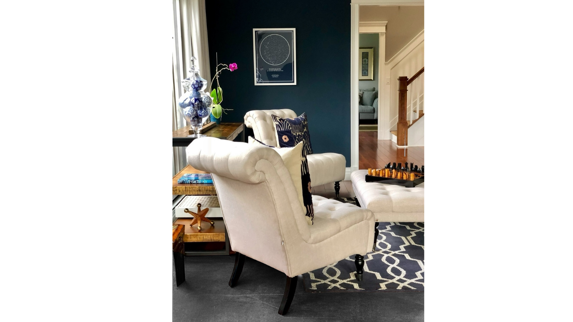 Elegant cream armchair in a dark teal living room with patterned rug and framed wall art at CRAFTED 1111 fashion