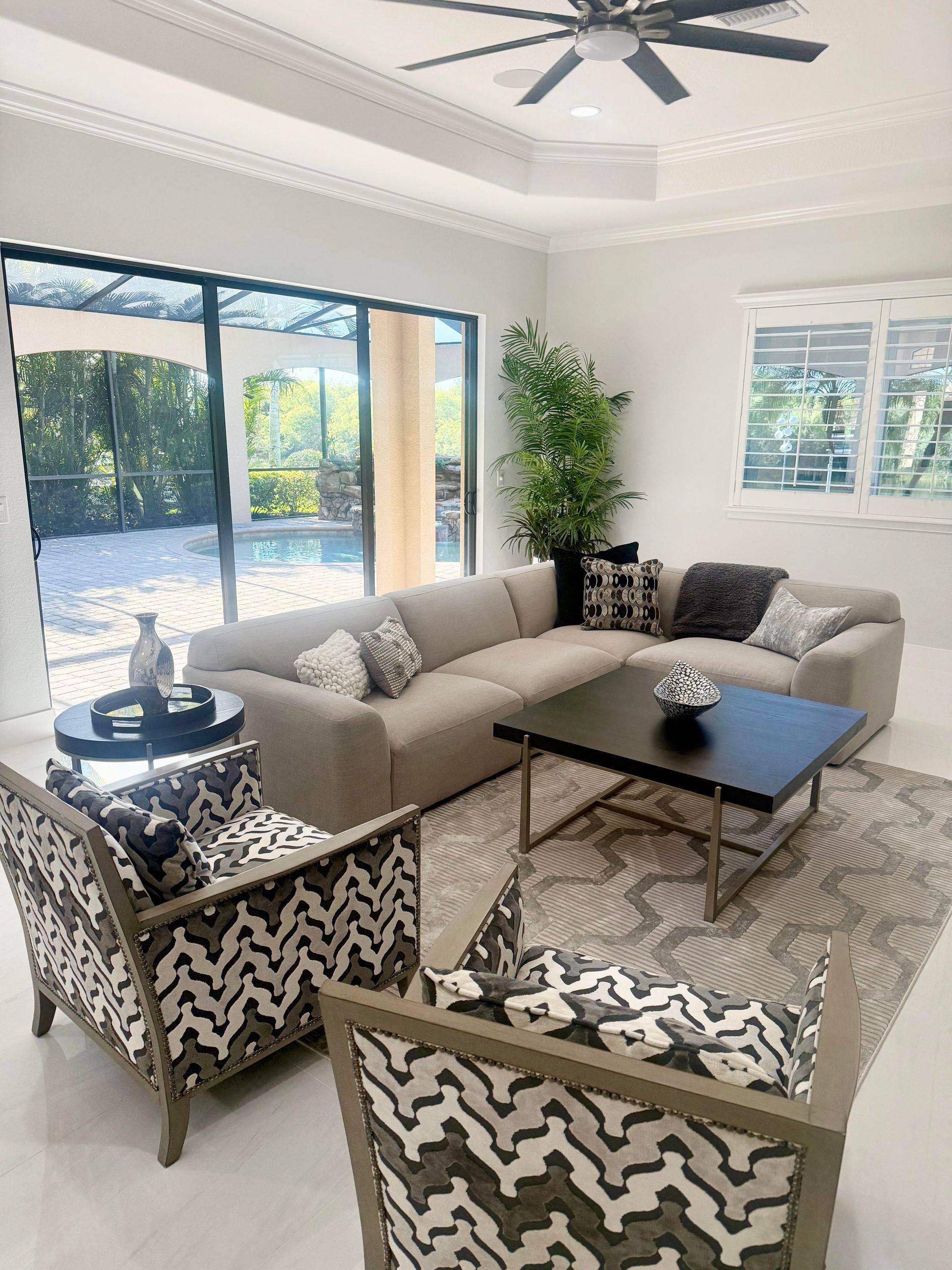 Bright modern living room with beige sofa, patterned chairs, black coffee table, and large windows at CRAFTED 1111 fashion
