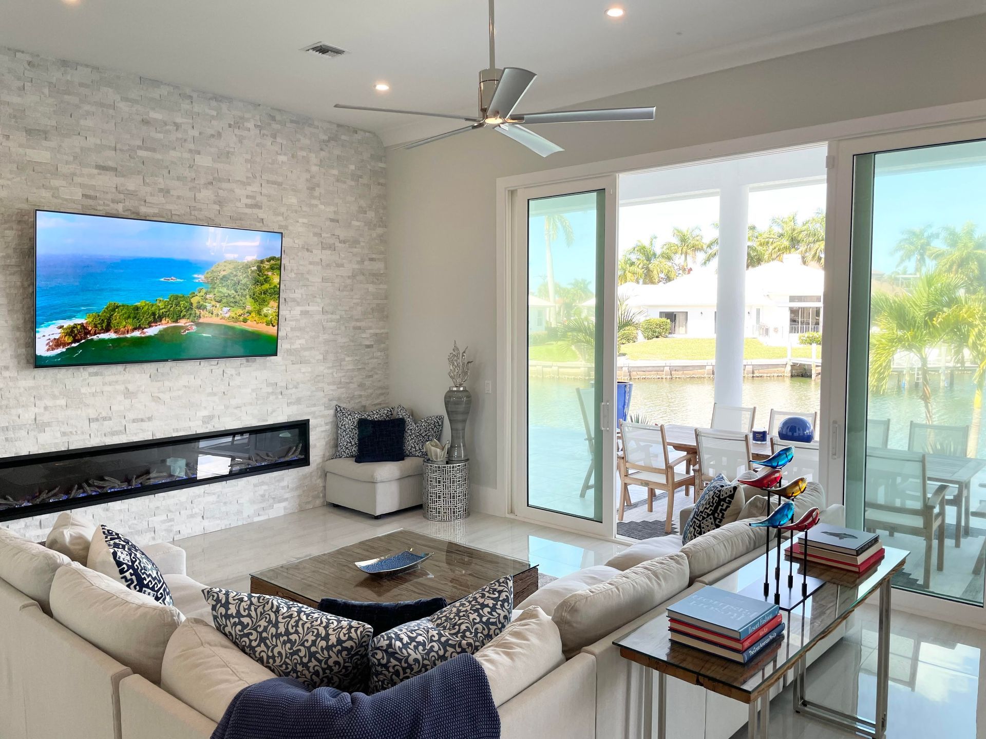 Bright modern living room with beige sectional, wall TV, ocean artwork, and glass doors to a sunny patio at CRAFTED 1111 fashion