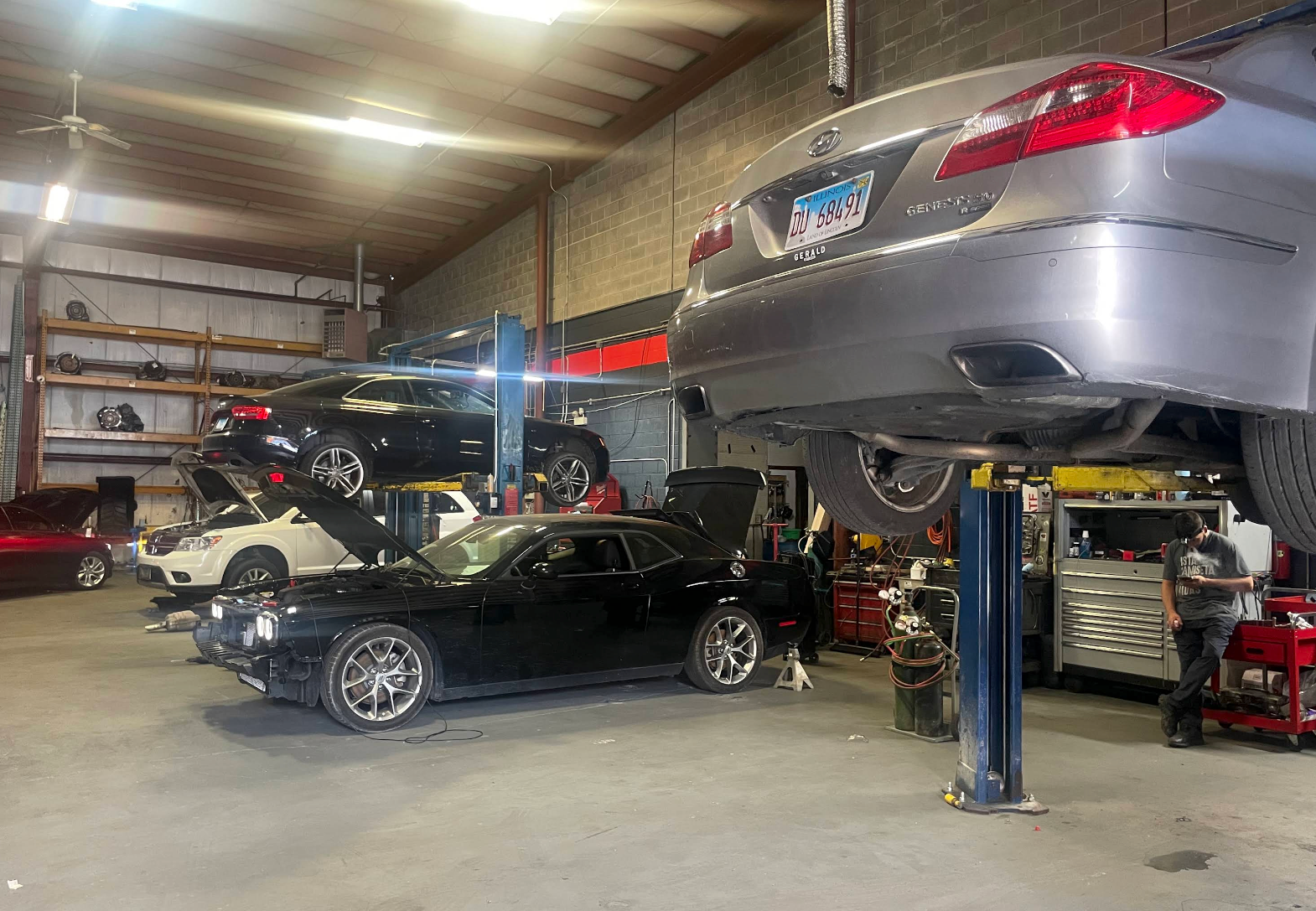 Auto repair shop with two raised cars and a black convertible on the floor | Auto Logic Complete Auto Repairs