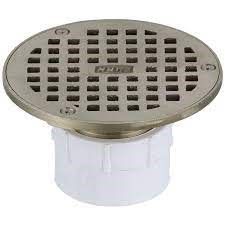 A round, metal drain cover on a white PVC pipe.