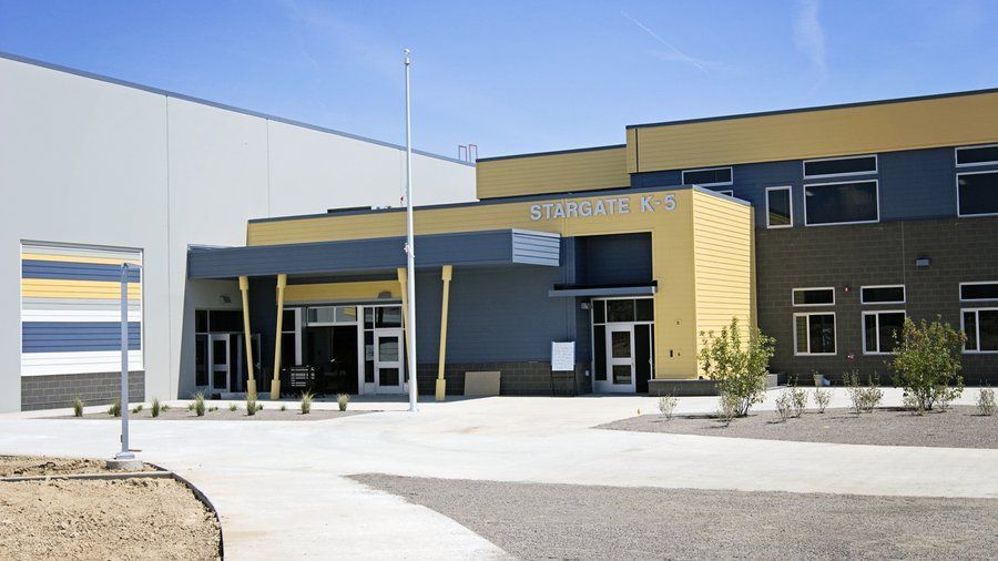 School entrance with yellow and blue facade under a clear, sunny sky.