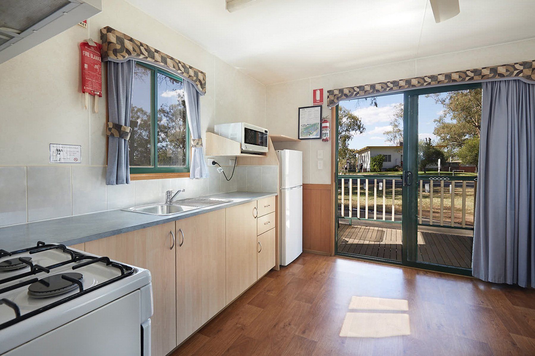 Apex Riverbeach Holiday Park cabin's kitchen with a stove , sink , refrigerator and sliding glass doors leading to a balcony .