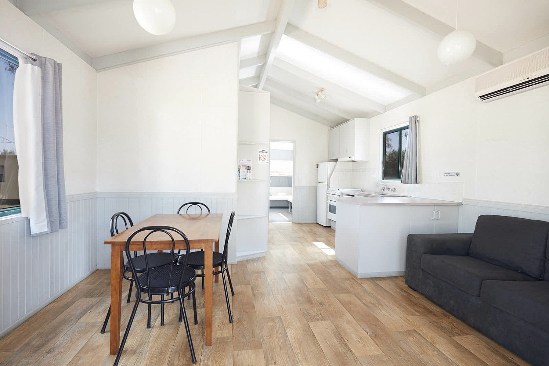 Apex Riverbeach Holiday Park Cabin lounge with full kitchen, table and chairs and comfy sofa