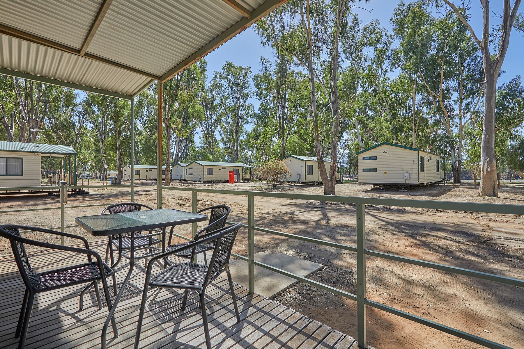 Apex Riverbeach Holiday Park cabin's front deck ,  trees in the background .