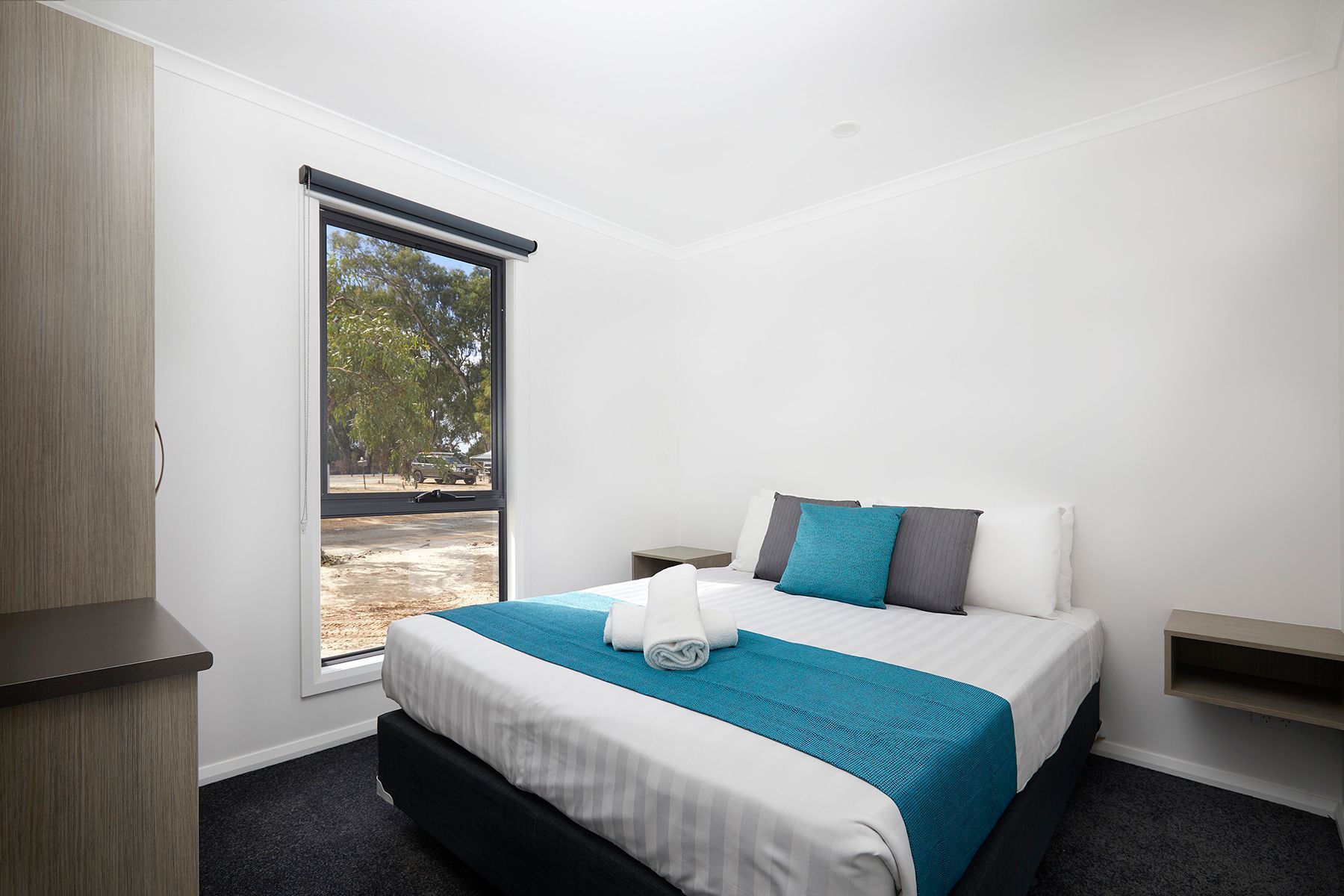 Apex Riverbeach Holiday Park cabin with bed, outlook to natural landscape