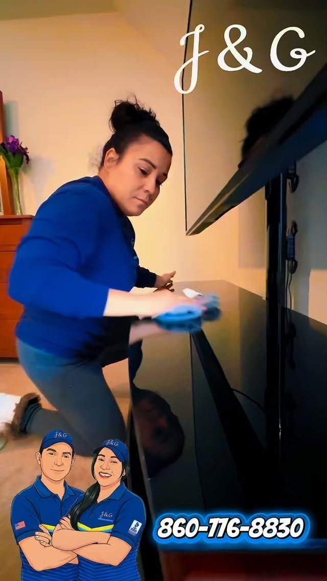 Person cleaning a black TV stand with a cloth in a living room, with “J&G” text and a phone number overlay.