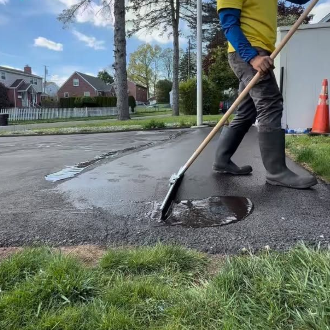 Worker patching a pothole on a wet residential street with a shovel
