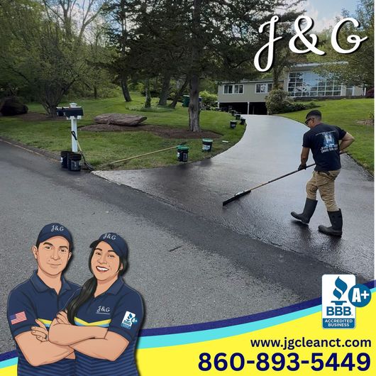 Two workers pressure washing a driveway outside a suburban home, with J&G branding and contact info.