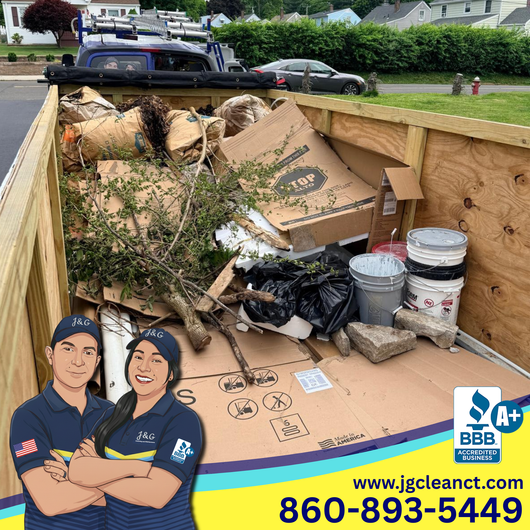 Dump trailer filled with cardboard, branches, and buckets on a residential street; JG Cleanout logo at bottom.