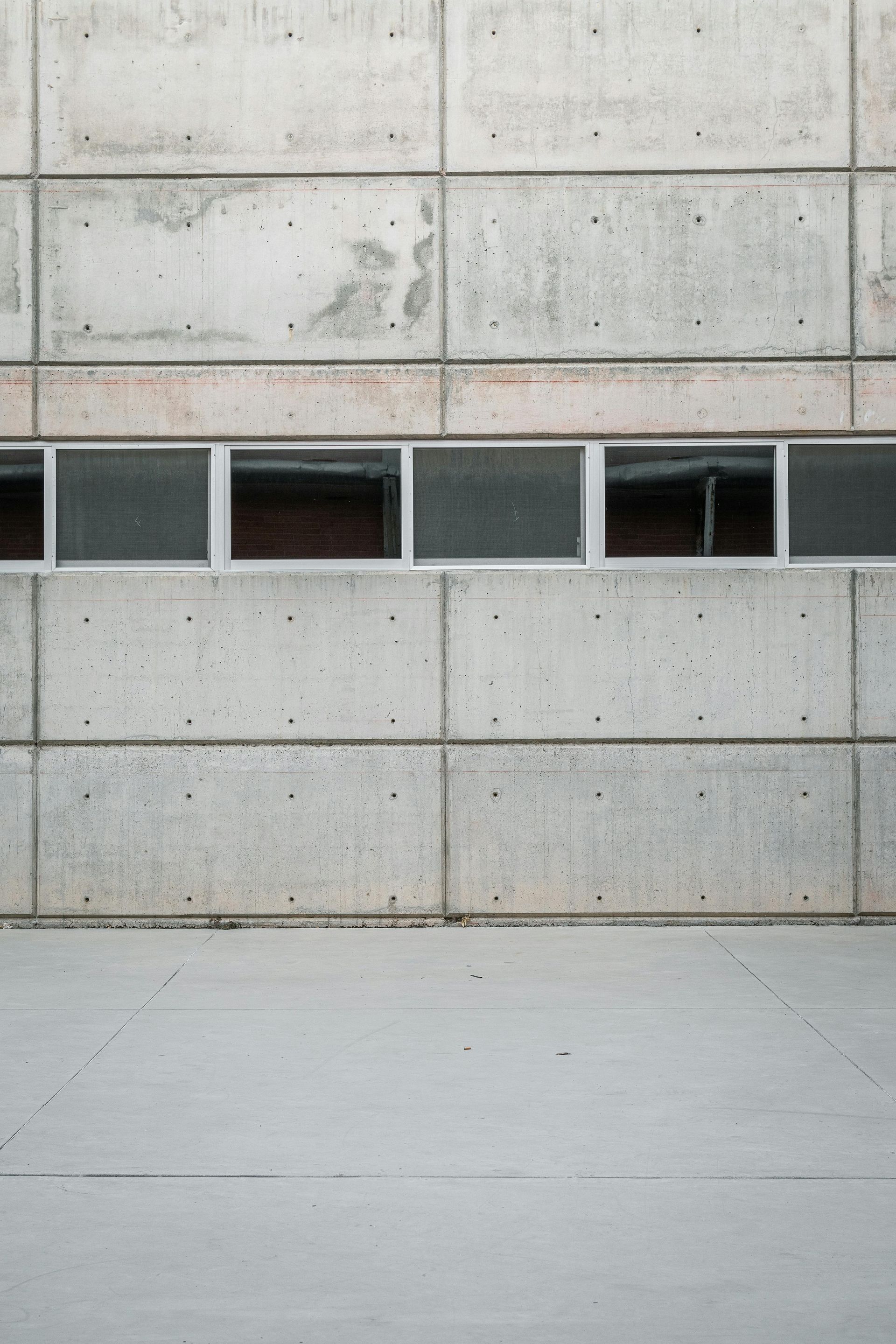 Concrete wall with a narrow row of small windows above a smooth gray floor
