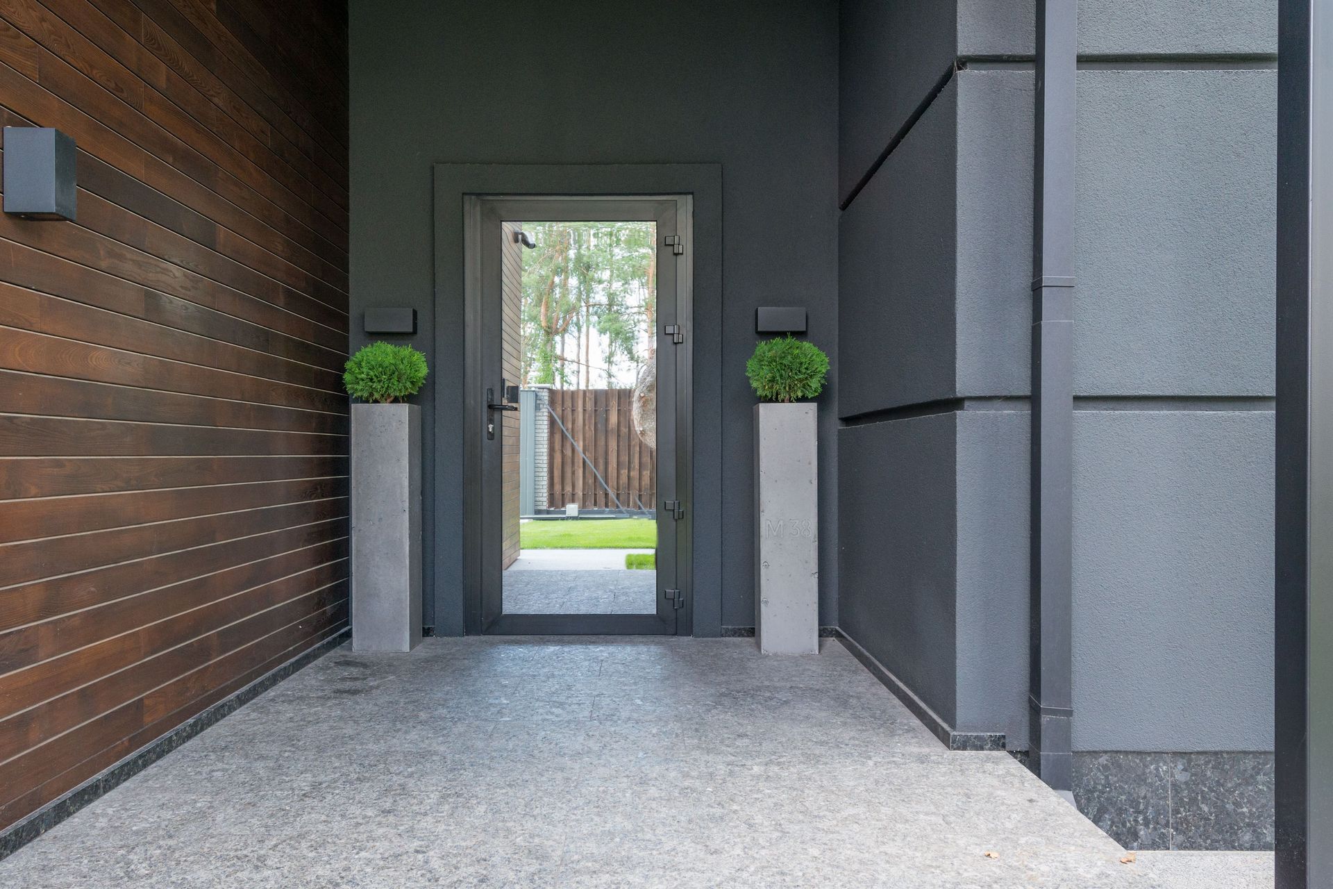 Modern front entryway with wood wall, gray stone, and a glass door leading to a courtyard.