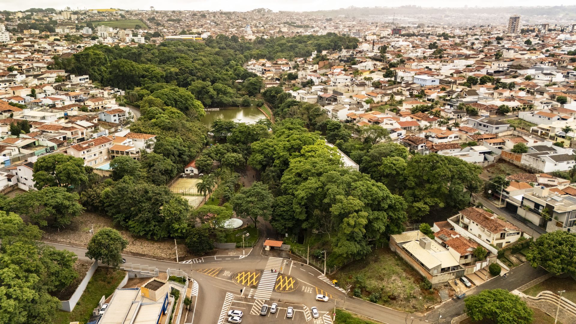 Pessoas caminhando em área urbana arborizada de Patos de Minas