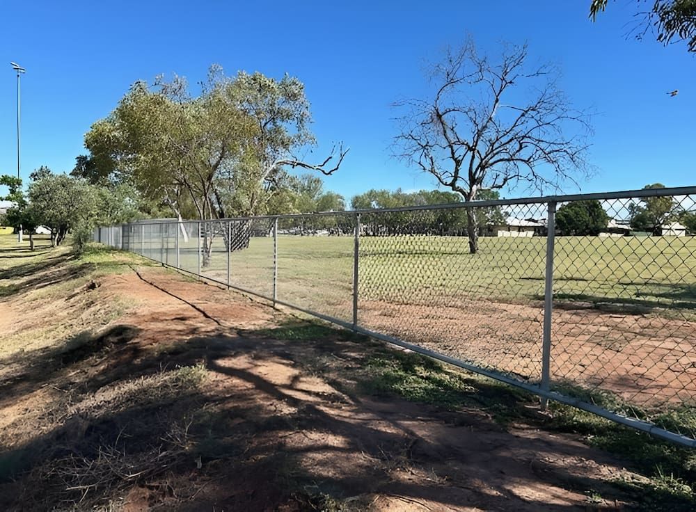 A Chain Link Fence Surrounds A Field With Trees — PH Davie in Cloncurry, QLD