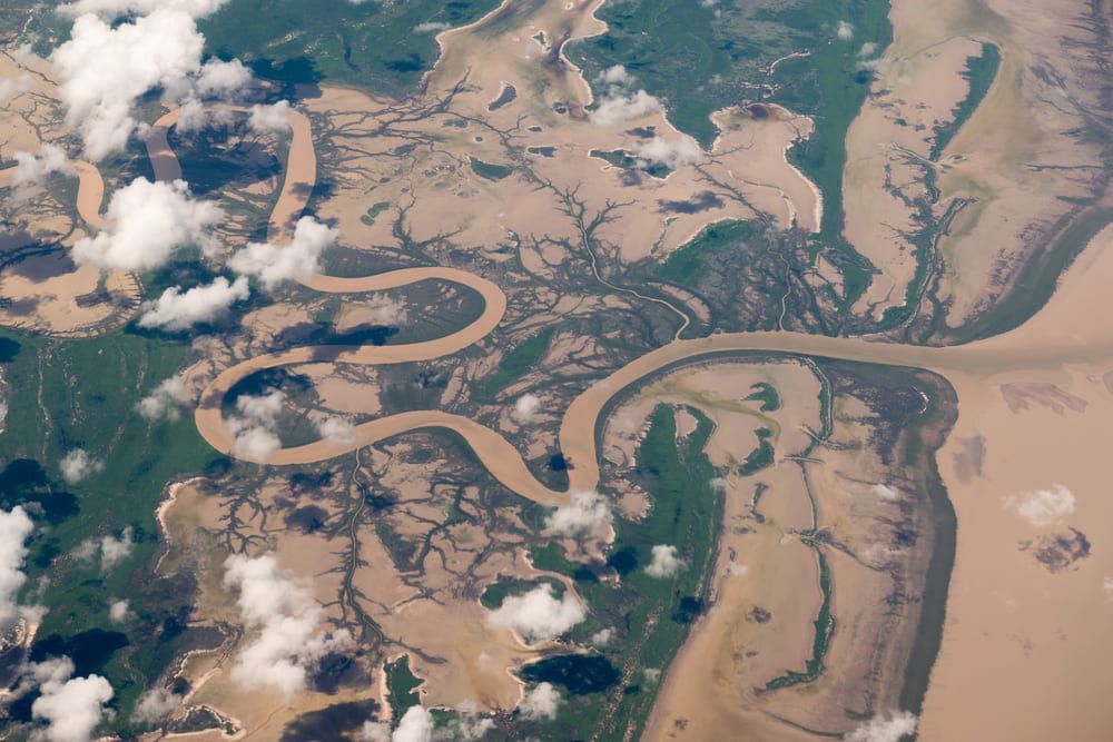 An Aerial View Of A River Surrounded By Trees And Clouds — PH Davie in Normanton, QLD
