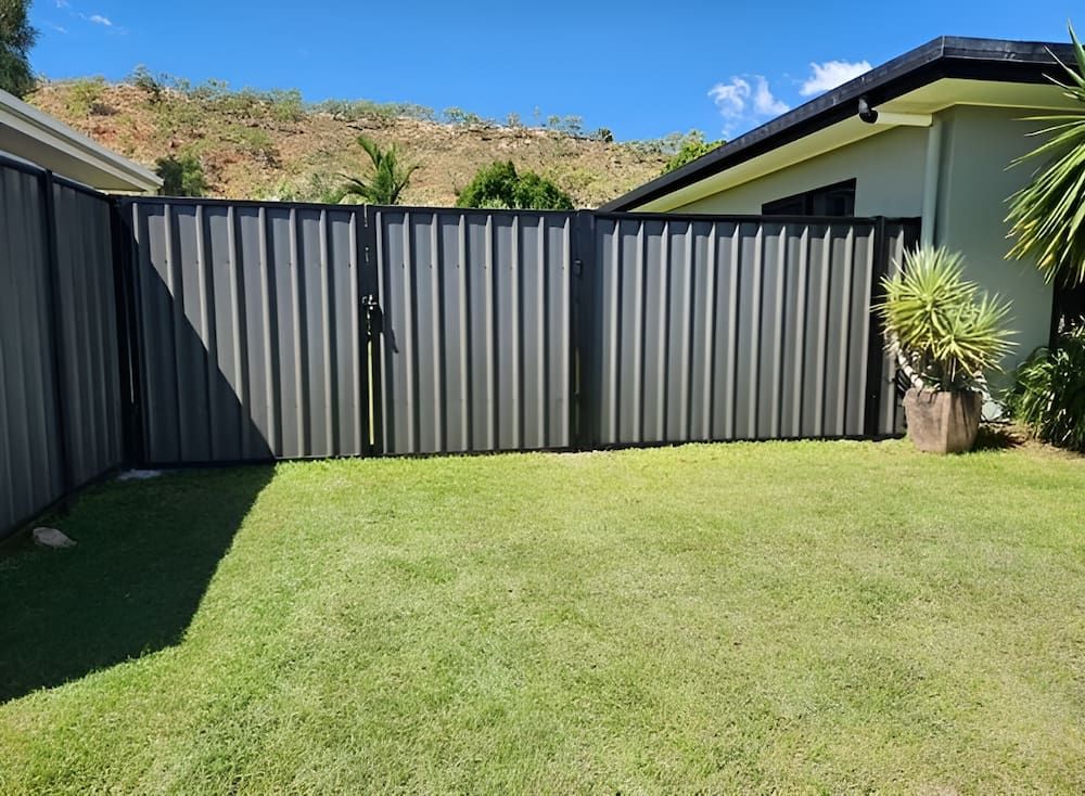 A Fence Is Surrounding A Lush Green Lawn In Front Of A House — PH Davie in Cloncurry, QLD