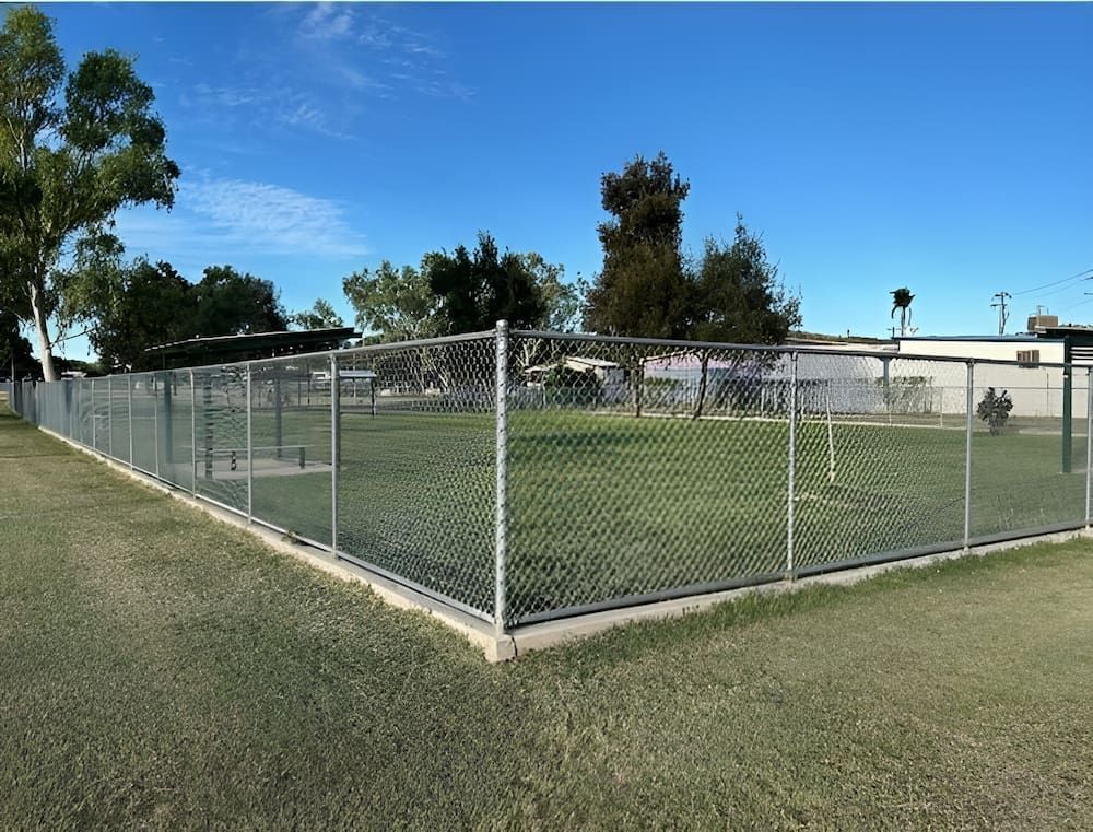 A Chain Link Fence Surrounds A Lush Green Field — PH Davie in Karumba, QLD