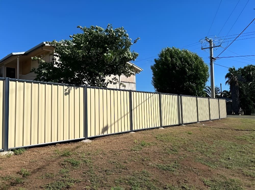 A Yellow Fence Surrounds A Grassy Field In Front Of A House — PH Davie in Boulia, QLD