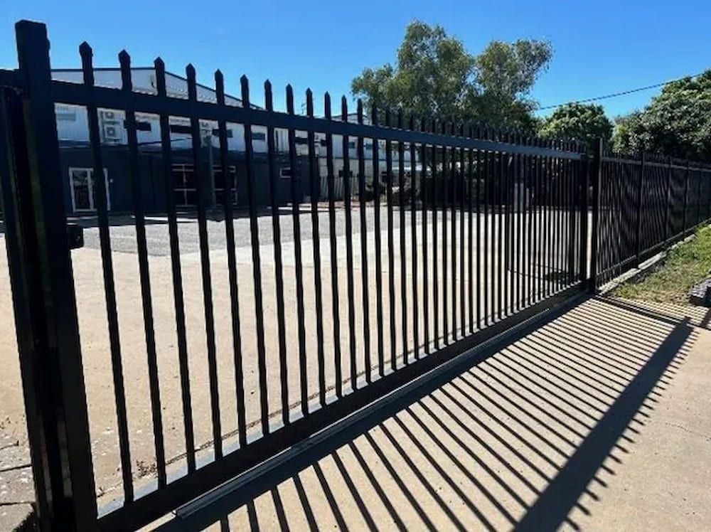 A Black Metal Fence With A Shadow On The Sidewalk — PH Davie in Mount Isa, QLD