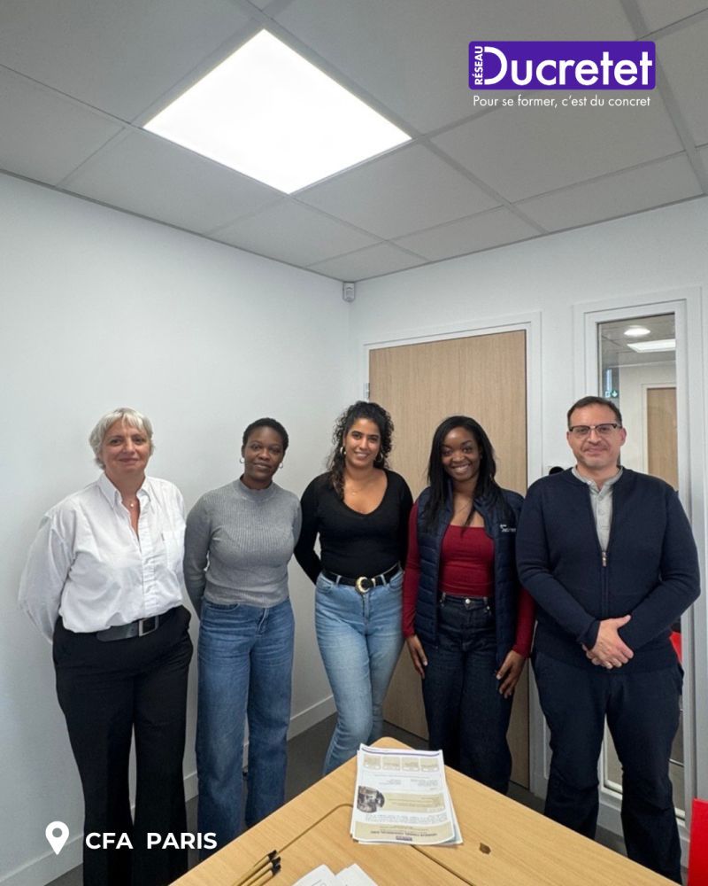 Group of five people posing in an office meeting room, with a Ducretet sign and CFA Paris logo visible.