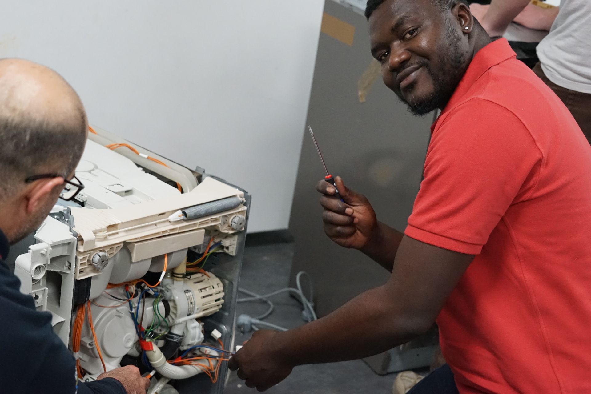 Photo d'un apprenant et son formateur en train de réparer une machine