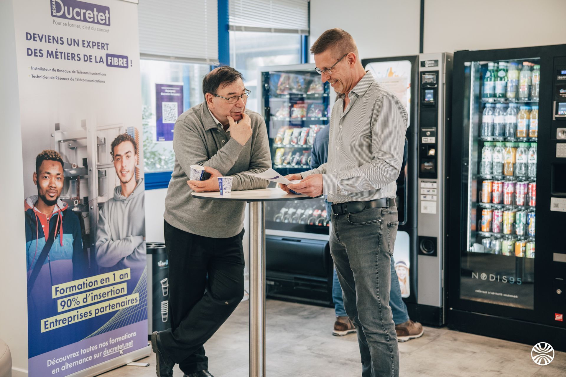 Deux hommes discutent devant un distributeur automatique