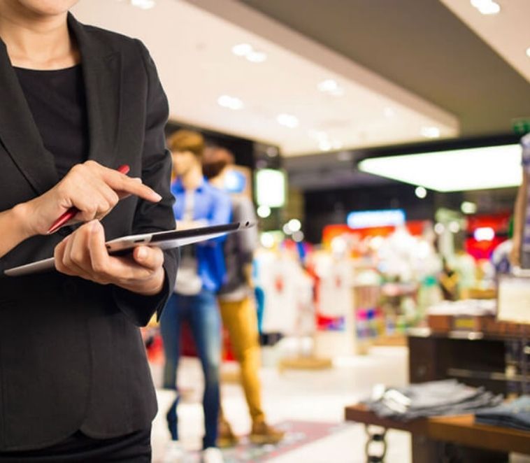 Femme dans un blazer noir qui utilise une tablette dans un magasin de vêtements.