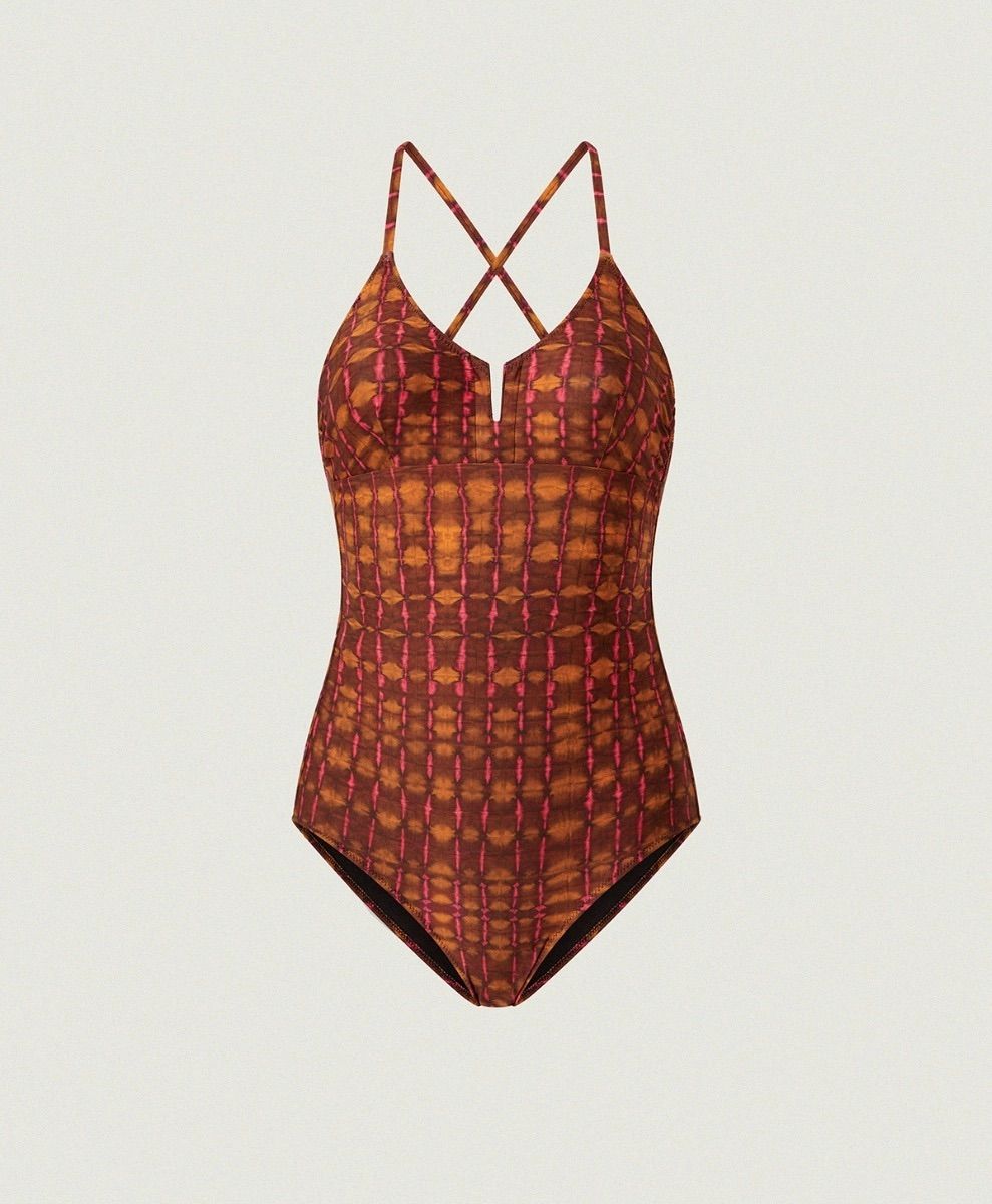 Costume intero con spalline incrociate e stampa geometrica rossa e arancione su sfondo bianco.