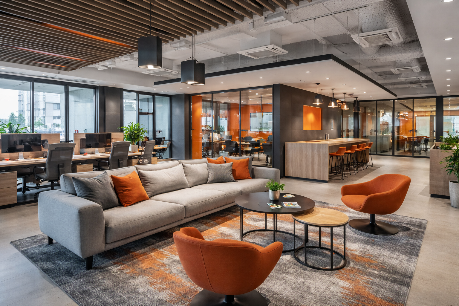 Een moderne kantoorlounge met een grijze hoekbank, twee oranje fauteuils en salontafels op een vloerkleed met patroon.