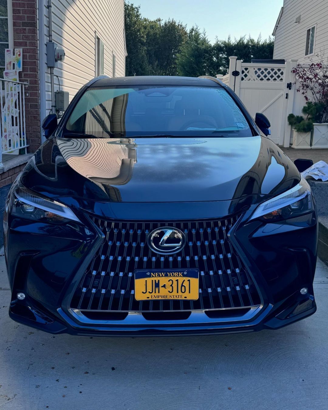A black lexus is parked in front of a white house