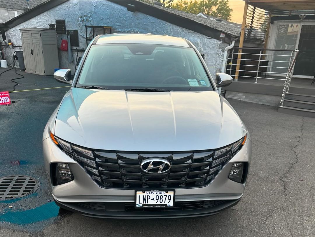 A silver hyundai tucson is parked in front of a building.