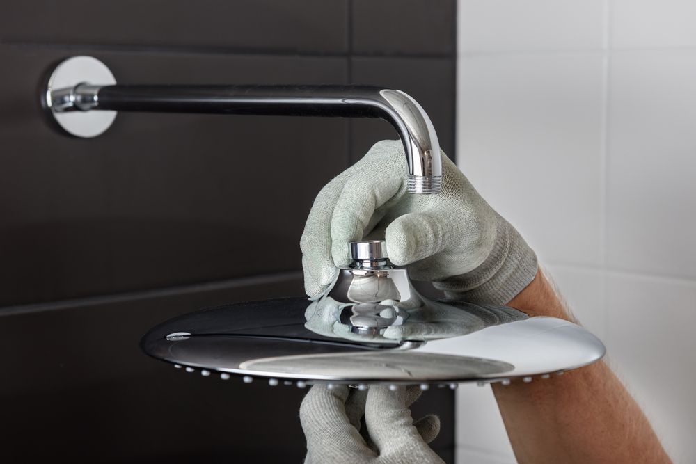 Plumber wearing gloves adjusting a chrome sink faucet.