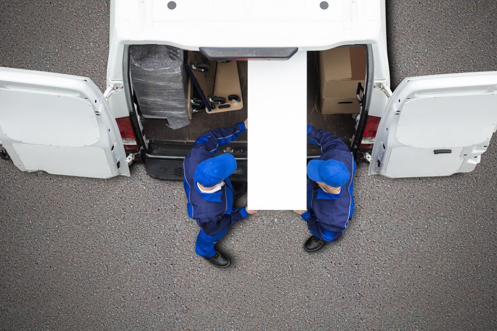 Two men are carrying a large piece of furniture into a van.