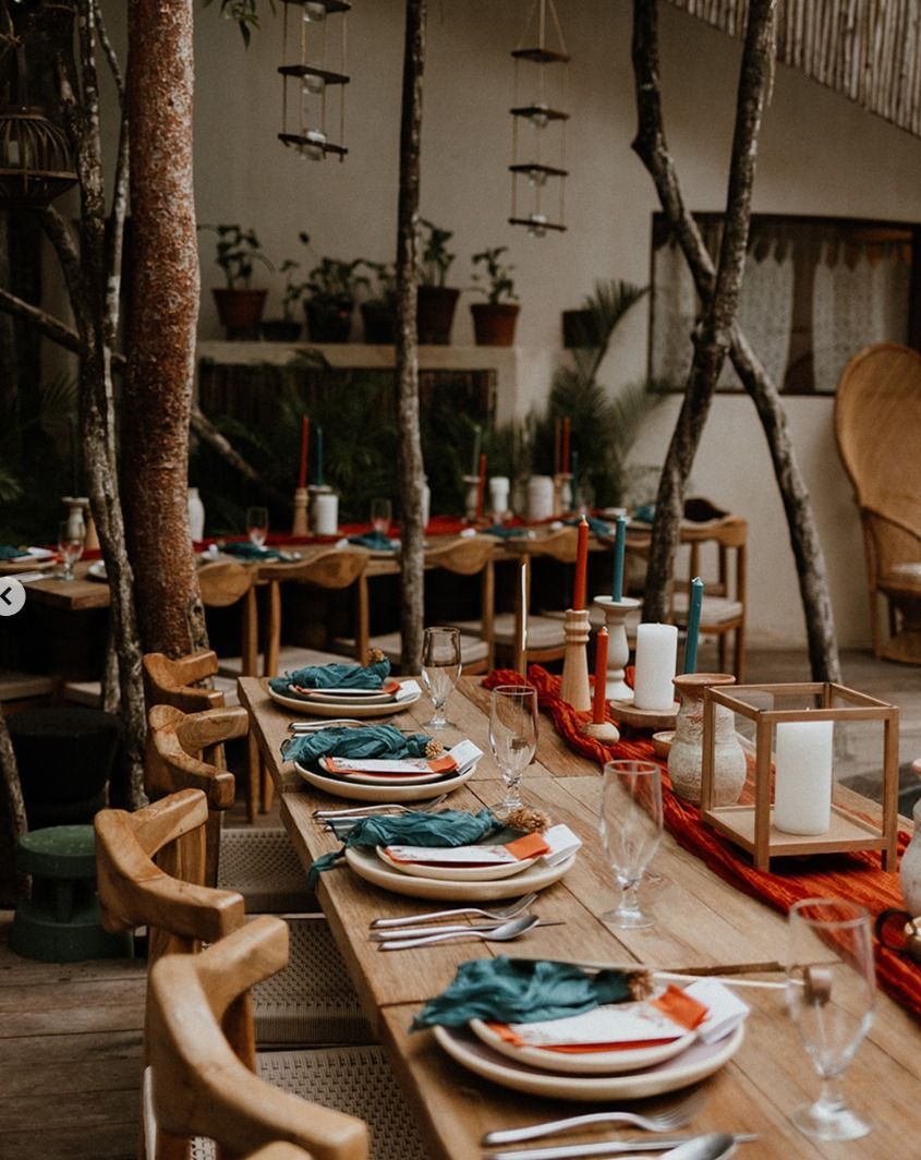 Long wooden dining table set with plates and teal napkins in a rustic indoor room