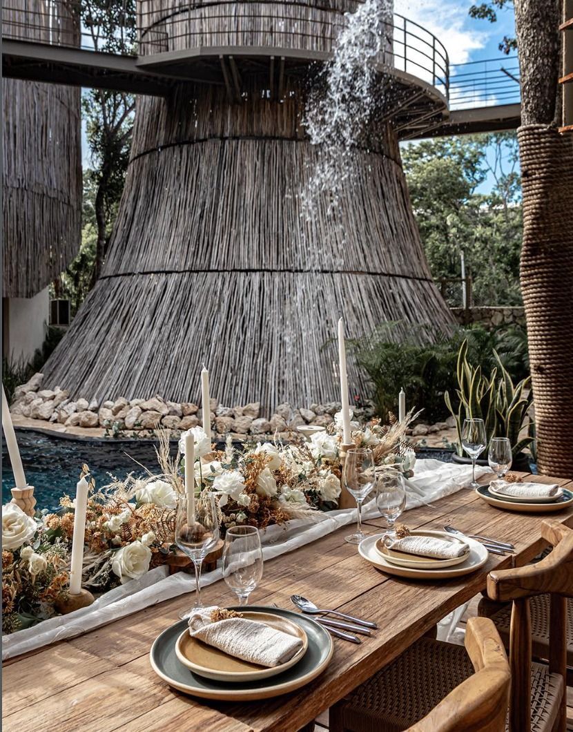 Elegant outdoor dining table beside a cascading water feature in a tropical resort setting
